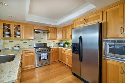 a kitchen with wooden cabinets and a stainless steel refrigerator at Coastal Luxury with Panoramic Ocean View in Oceanside
