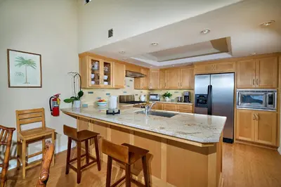 a kitchen with wooden cabinets and a stainless steel refrigerator at Coastal Luxury with Panoramic Ocean View in Oceanside