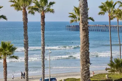 a view of a beach with palm trees and a pier at Coastal Luxury with Panoramic Ocean View in Oceanside