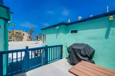 a green building with a bench on a deck at Manhattan Shores 1A in San Diego