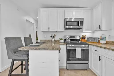 a kitchen with white cabinets and a stove top oven at Cozy Coastal Escape Beach & Brews in San Diego
