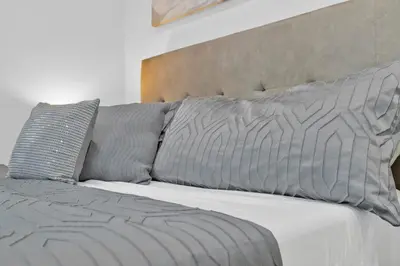 a bed with two pillows and a gray blanket at Cozy Coastal Escape Beach & Brews in San Diego