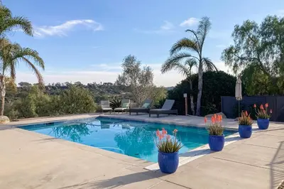 a swimming pool with plants in blue vases at Canyon Paradise in Encinitas