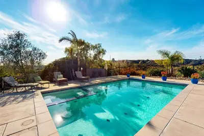 a swimming pool with blue water in a yard at Canyon Paradise in Encinitas