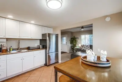 a kitchen with white cabinets and a wooden table at Home to enjoy the beach with ocean view in Oceanside