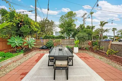a patio with a table and chairs in a garden at Carlsbad Beach Bungalow in Carlsbad