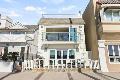 a large white house with a white fence at Beachfront Getaway with Ocean Views and Private Patio in Newport Beach