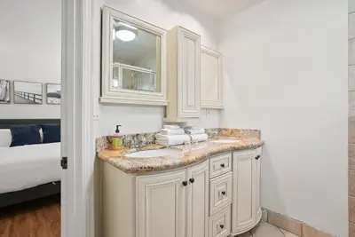 a white bathroom with a sink and a bed at Beachfront Getaway with Ocean Views and Private Patio in Newport Beach