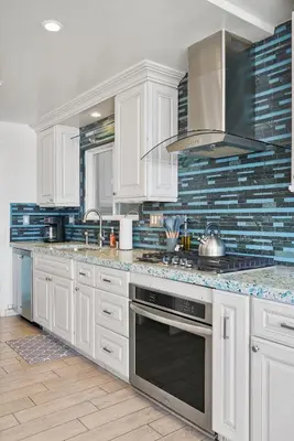 a kitchen with white cabinets and a stove top oven at Beachfront Retreat with Ocean Views Private Rooftop Deck Walk to Pier and Town in Newport Beach