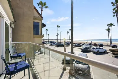 a balcony with chairs and a view of a parking lot at Beachfront Retreat with Ocean Views Private Rooftop Deck Walk to Pier and Town in Newport Beach