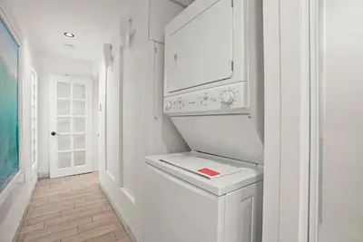 a white laundry room with a washer and dryer at Beachfront Retreat with Ocean Views Private Rooftop Deck Walk to Pier and Town in Newport Beach