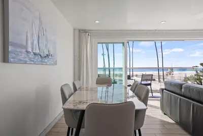 a dining room with a table and a view of the ocean at Beachfront Retreat with Ocean Views Private Rooftop Deck Walk to Pier and Town in Newport Beach