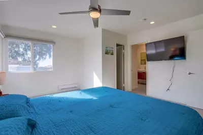a bedroom with a blue bed and a flat screen tv at 2nd floor A-C steps to beach downtown La Jolla in San Diego