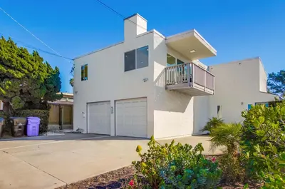 a white house with a balcony and a driveway at 2nd floor A-C steps to beach downtown La Jolla in San Diego