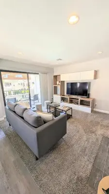 a living room with a large couch and a television at Poolside 2BR Condo with Balcony & Workspace in San Diego