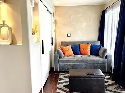 a living room with a couch with orange and blue pillows at Private Bedroom & Bathroom Grove, Pool & City View in Oceanside