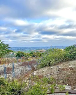 a fence on top of a hill with trees at Private Bedroom & Bathroom Grove, Pool & City View in Oceanside