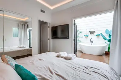 a white bedroom with a tub and a bed and a bathroom at 3 blocks to ocean luxury patio nightlife in San Diego