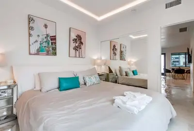 a white bedroom with a large bed with blue pillows at 3 blocks to ocean luxury patio nightlife in San Diego