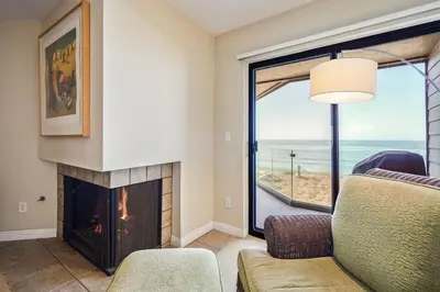 a living room with a fireplace and a view of the ocean at SurfSong Dream - Beachfront in Solana Beach