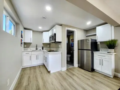 a kitchen with white cabinets and stainless steel appliances at The Grove Studio at Mt Helix in La Mesa