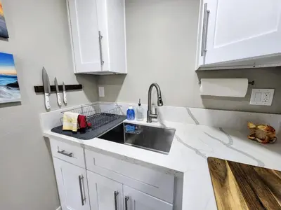 a kitchen with white cabinets and a sink at The Grove Studio at Mt Helix in La Mesa