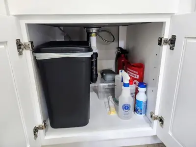 a cabinet with a trash can and cleaning products in it at The Grove Studio at Mt Helix in La Mesa