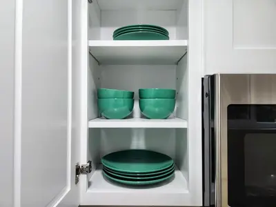 a kitchen cabinet with green plates and bowls in it at The Grove Studio at Mt Helix in La Mesa