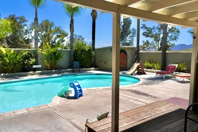 a swimming pool with a person sitting in a chair next to a house at La Casita Poolside Retreat in Lake Elsinore