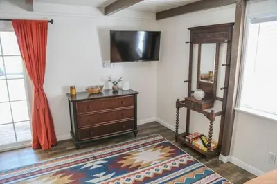 a living room with a dresser and a television on the wall at La Casita Poolside Retreat in Lake Elsinore