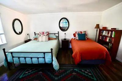 a bedroom with two beds and a mirror at La Casita Poolside Retreat in Lake Elsinore
