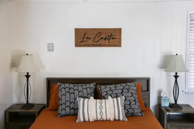 a bed with two lamps and a sign on the wall at La Casita Poolside Retreat in Lake Elsinore