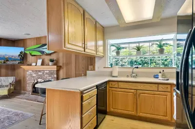 a kitchen with wooden cabinets and a window at Hot Tub, Fire Pit, BBQ, Shuffleboard, Walk To Beach in Carlsbad