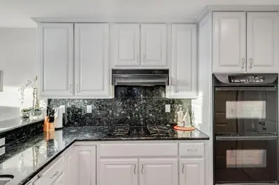 a kitchen with white cabinets and a stove top oven at Navigate Stays Front Row to Paradise in San Diego