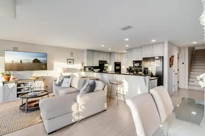a living room with white furniture and a kitchen at Navigate Stays Front Row to Paradise in San Diego