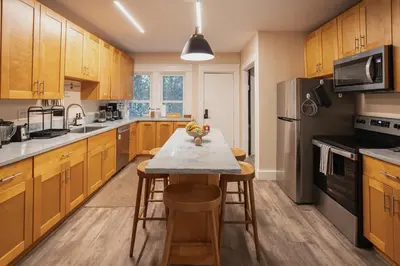a kitchen with wooden cabinets and a table with stools at Outsite San Diego - Golden Hill in San Diego
