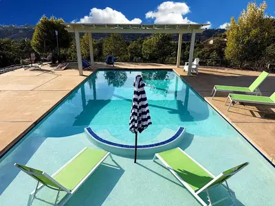 a swimming pool with two lawn chairs and an umbrella at Hilltop Villa & Guesthouse, Pool Oasis, Pickleball Court in Fallbrook