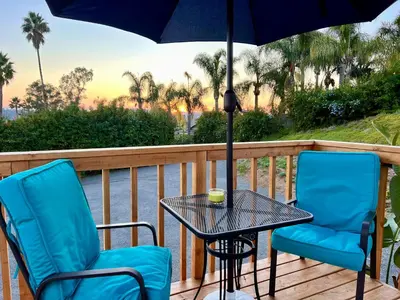 two chairs and a table on a deck with an umbrella at Tiny House on private large property in Vista