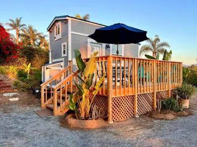 a house with a deck with an umbrella at Tiny House on private large property in Vista