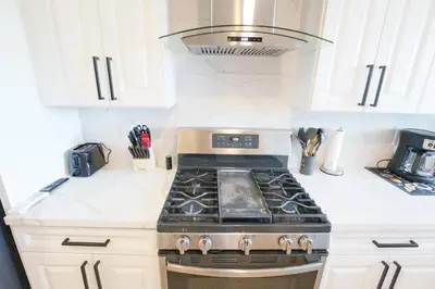 a stove top oven in a kitchen with white cabinets at Exotic home Rogers road in Spring Valley