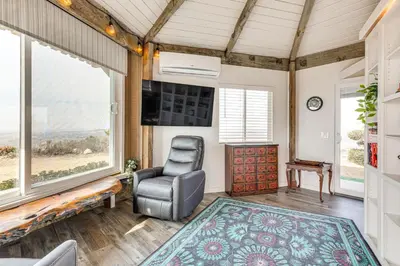 a living room with a chair and a large window at Backyard and Zen Garden Hilltop Haven in Bonsall! in Vista