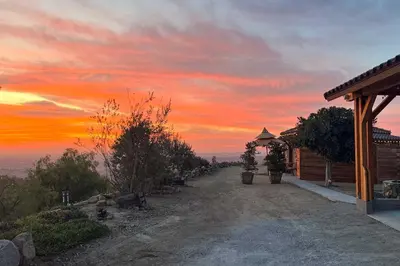 a sunset over a yard with a house and a building at Backyard and Zen Garden Hilltop Haven in Bonsall! in Vista