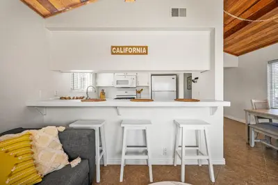 a kitchen with a bar with stools and a couch at 3BR Home Steps from Shops, Pier and Beach in Newport Beach