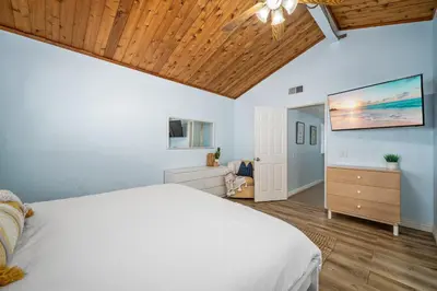 a bedroom with a white bed and a wooden ceiling at 3BR Home Steps from Shops, Pier and Beach in Newport Beach