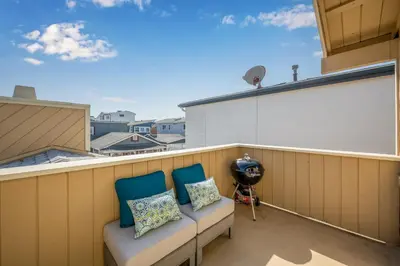 a balcony with two chairs and a fan at 3BR Home Steps from Shops, Pier and Beach in Newport Beach
