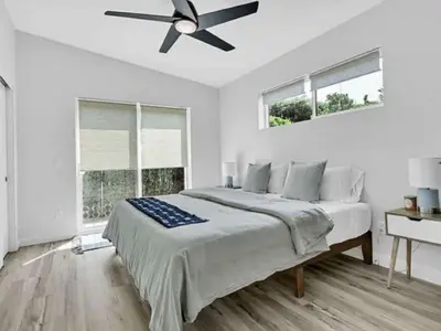 a white bedroom with a bed and a ceiling fan at The Quaint Cardiff Hideaway with Pak N Play in Encinitas