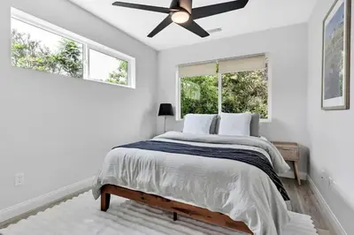 a white bedroom with a bed and a ceiling fan at The Quaint Cardiff Hideaway with Pak N Play in Encinitas