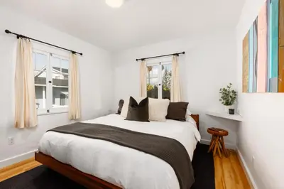 a white bedroom with a large bed and two windows at ENC-1035 - Charming Coastal Cottage in Encinitas