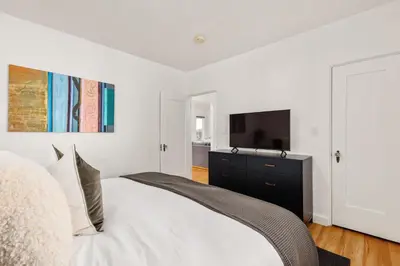 a white bedroom with a bed and a tv at ENC-1035 - Charming Coastal Cottage in Encinitas