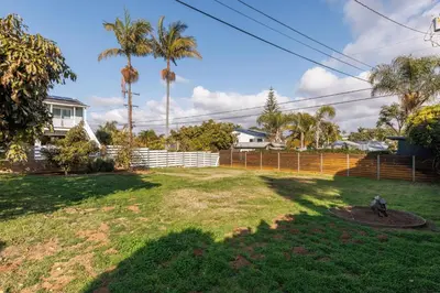 a yard with palm trees and a fence at ENC-1035 - Charming Coastal Cottage in Encinitas